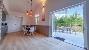 A modern kitchen with a dining area, wooden flooring, and a large sliding glass door leading to an outdoor patio.