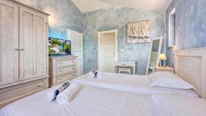 A hotel room with a large wardrobe, a bed with white linens, a television, and a painting on the wall. - Villa Milo Mali Vareski With Pool (Marcana)