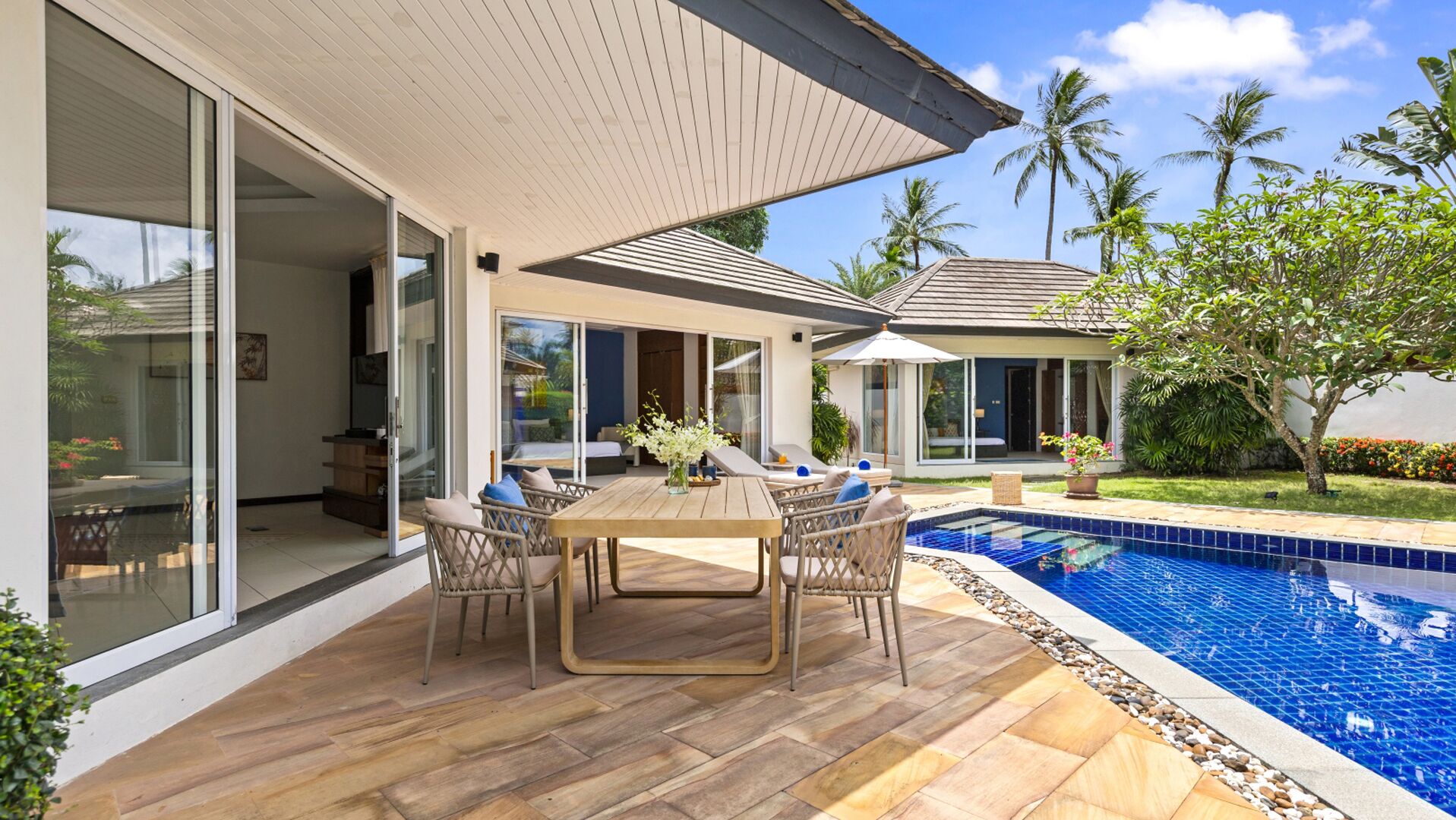 Ein modernes Haus mit Pool, Schiebegläsern und Gartenmöbeln.