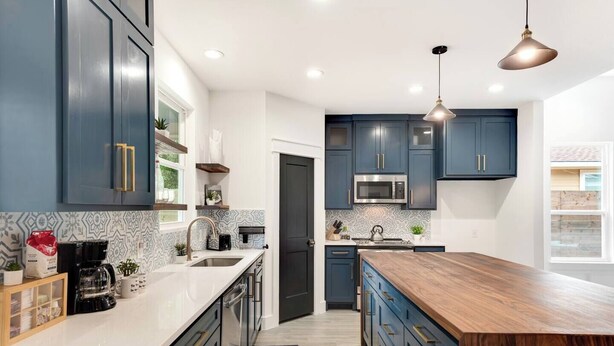 A modern kitchen with dark blue cabinets, a wooden island, and a stainless steel microwave. - Luminous and Cozy 3BR 2Bath Escape (Lexington)