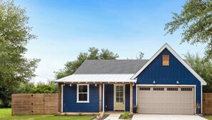 A single-story house with a blue exterior, a grey roof, and a white garage door. - Luminous and Cozy 3BR 2Bath Escape (Lexington)