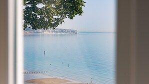 Blick auf die Küste mit ruhigem Wasser, einem Sandstrand und einer Klippe im Hintergrund.