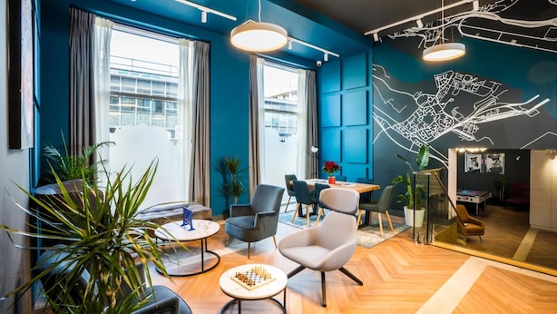 Ein modernes Hotelzimmer mit großem Fenster, Essbereich und Stadtbild-Wandgemälde.
