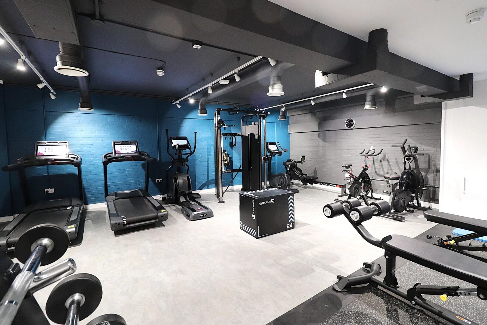 Et fitnessrum med løbebånd, crosstrainere, vægtbænke og håndvægte.
