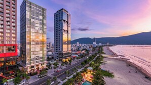 Un paisaje urbano costero con modernos edificios de gran altura, una playa y una zona de piscina.
