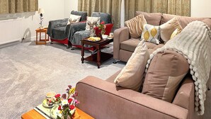 A living room with two sofas, a coffee table, and a side table with a floral arrangement. - Providing the perfect mix of countryside tranquillity and coastal adventure. (Pinwherry, near Girvan)
