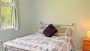 A bedroom with a bed, a window with curtains, a bedside table with a lamp, and a dresser. - Providing the perfect mix of countryside tranquillity and coastal adventure. (Pinwherry, near Girvan)