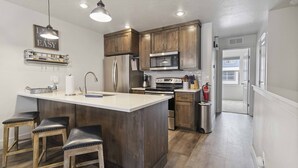 A kitchen with wooden cabinets, stainless steel appliances, and a bar stool seating area.