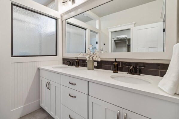 A bathroom with two sinks, a large mirror, and a window with frosted glass. - Upscale Parkside Retreat | High-End Kitchen | Office | 2 Bikes | Screened Porch | 2-Car Garage (Eagle)