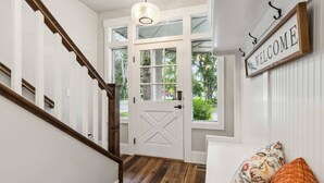 Un escalier avec des rampes en bois et une porte blanche dotée d’un panneau de verre.