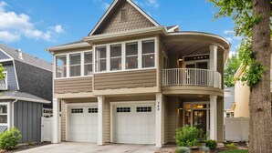 Une maison à deux étages avec un balcon, un garage et une pelouse bien entretenue.