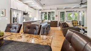 Une cuisine moderne équipée d’appareils électroménagers en acier inoxydable, un coin repas avec une table en marbre et un espace salon confortable avec des fauteuils en cuir.