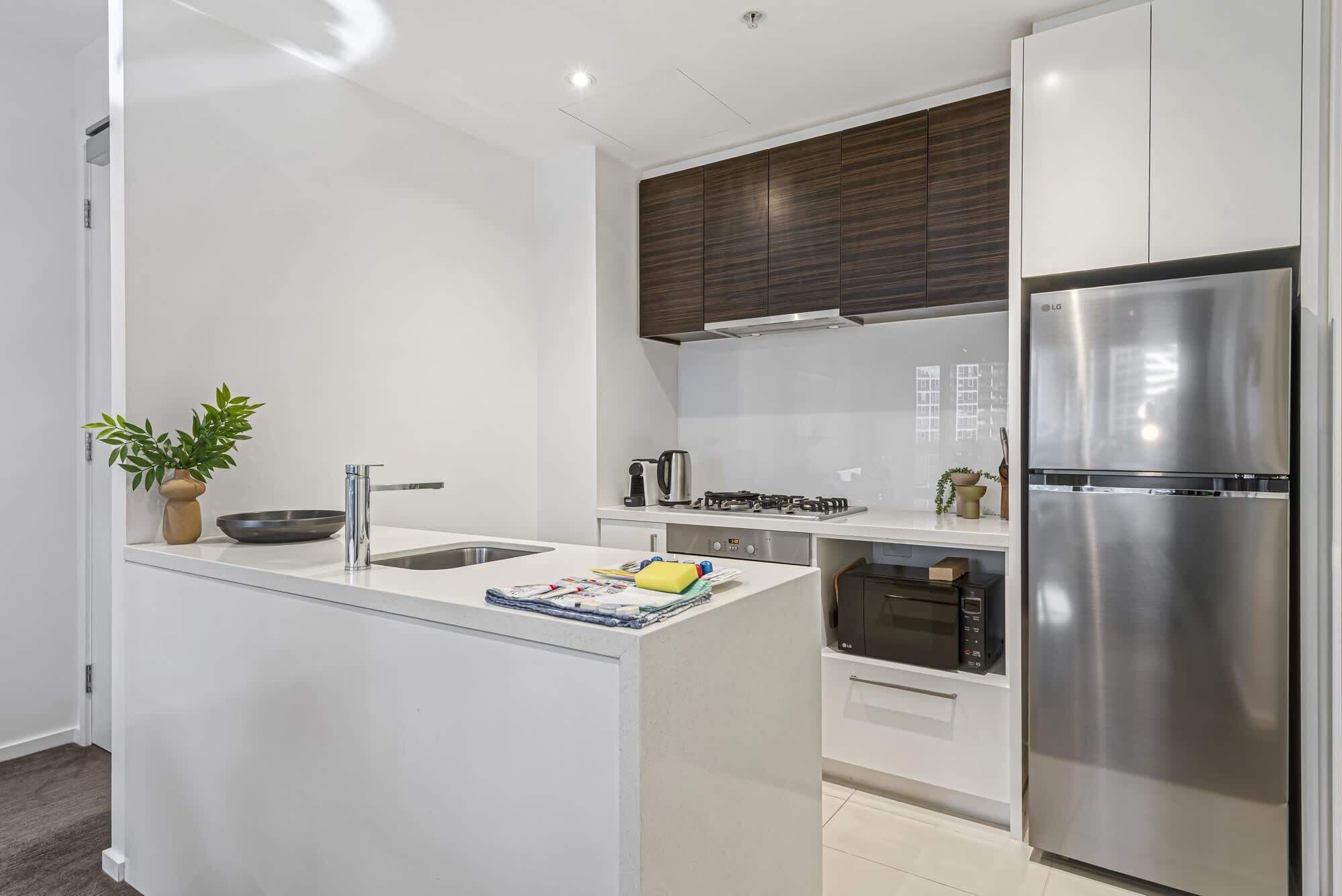 A modern kitchen with a central island, stainless steel appliances, and a dark wood cabinet.