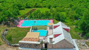 Une villa dotée d’une piscine, d’un court de tennis et de murs en pierre.