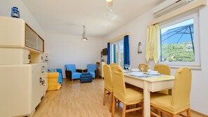 A room with a dining table, chairs, a television, and a window with a view.