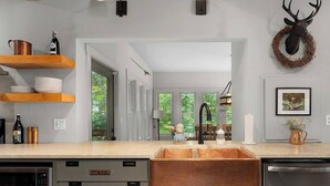 A modern kitchen with a large sink, wooden shelves, and a deer head decoration. - Private 6-Acre Retreat | Views, Hot Tub, Fire Pit (Ellijay)
