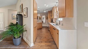 A kitchen with wooden cabinets, a refrigerator, and a potted plant. - Tropic Bliss l Pool Oasis l Mins to DNTN (St. Augustine)