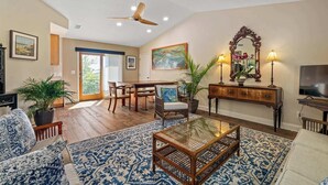 A spacious living room with a ceiling fan, a dining area, and a large mirror. - Tropic Bliss l Pool Oasis l Mins to DNTN (St. Augustine)