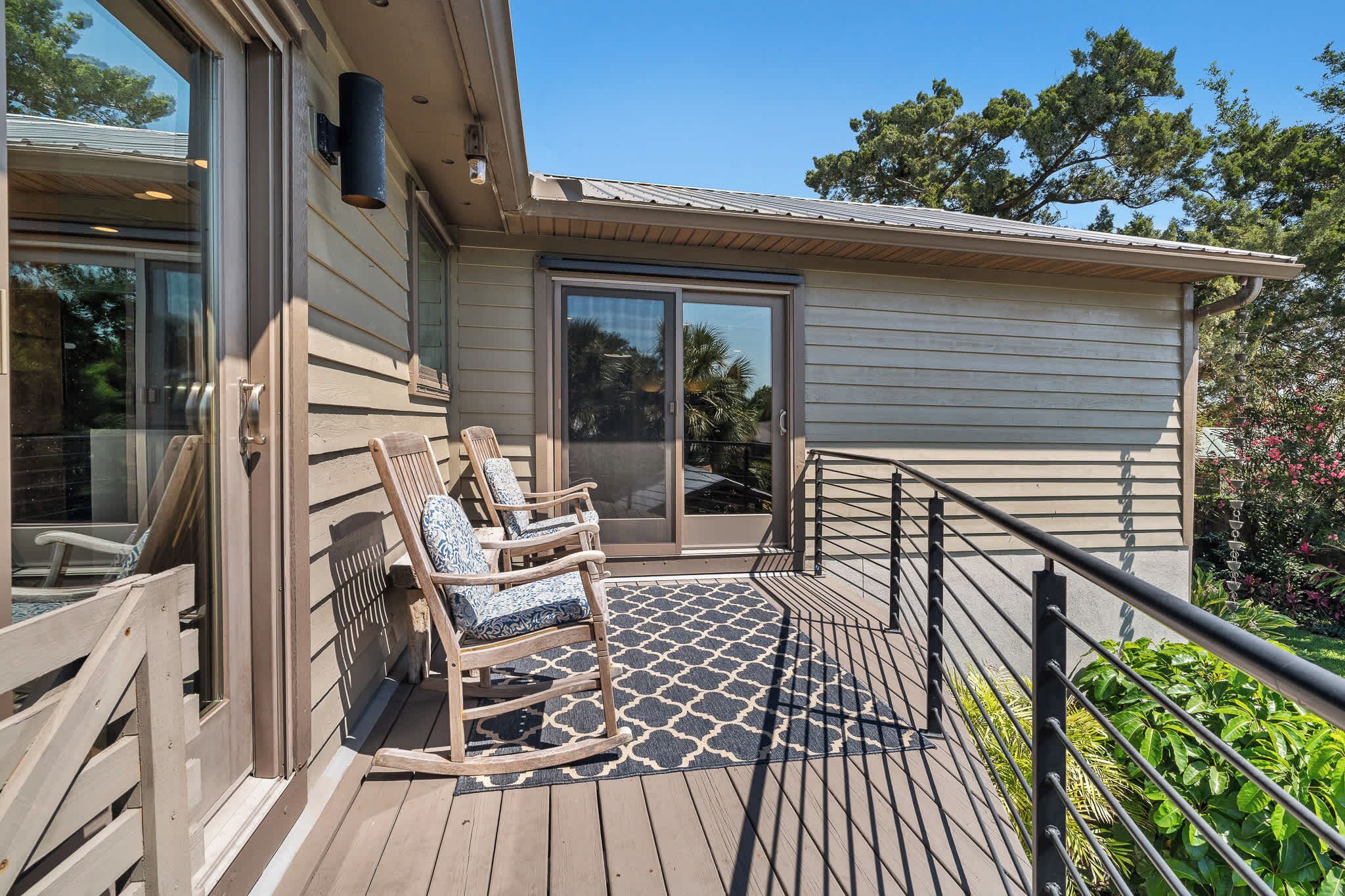 A deck with a wooden railing, two rocking chairs, and a glass door leading to a covered porch.