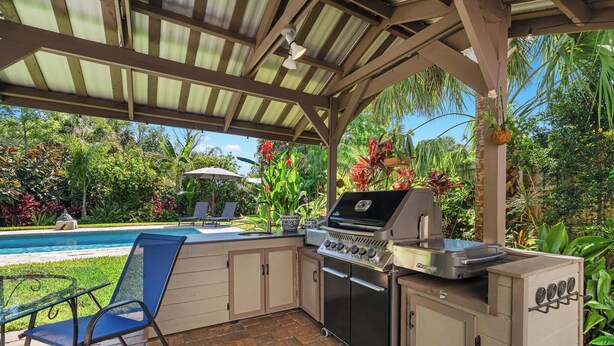 An outdoor kitchen with a grill, a sink, and a chair. - Tropic Bliss l Pool Oasis l Mins to DNTN (St. Augustine)