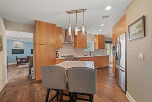 Una cucina moderna con mobili in legno, elettrodomestici in acciaio inossidabile e luci a sospensione.