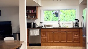 A modern kitchen with wooden cabinets, a built-in oven, and a window overlooking greenery.