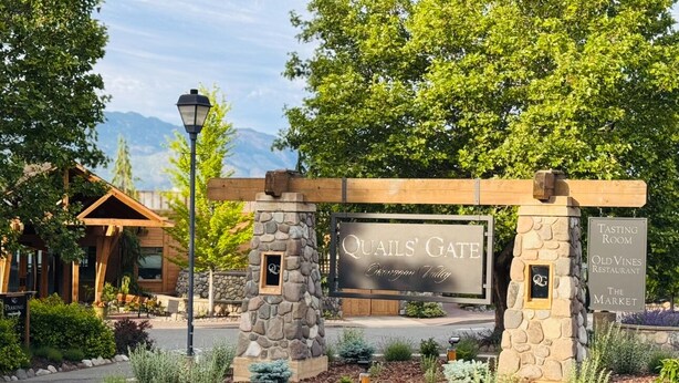 Quails' Gate entrance with a stone archway, a sign for the Tasting Room, and a sign for Old Vines Restaurant.