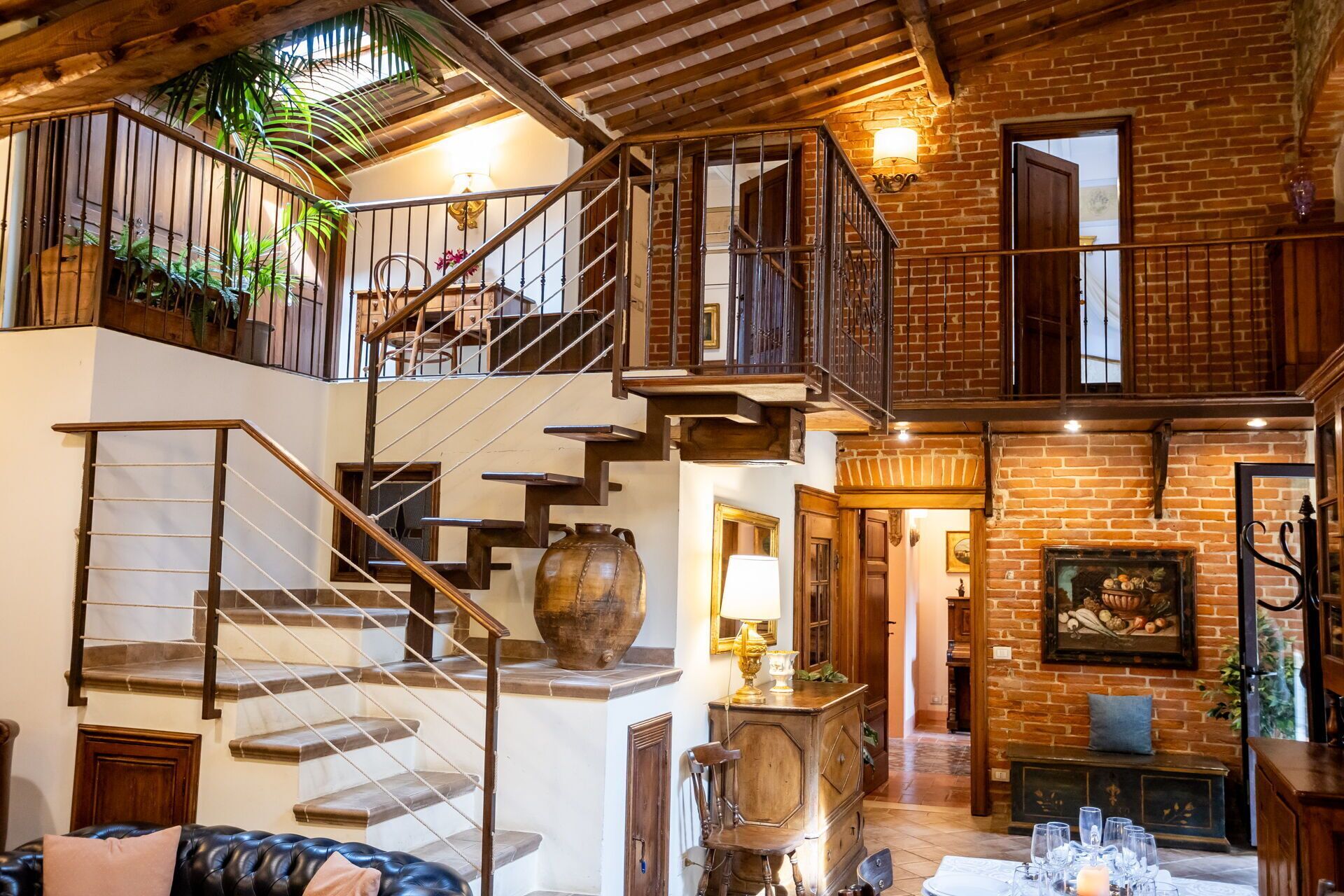 Un intérieur spacieux avec un escalier menant à un balcon, une cheminée et un coin repas.