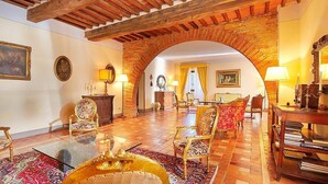 A spacious room with a high ceiling, a brick archway, and a mix of traditional and modern furnishings. - Villa Rama: A splendid seventeenth-century two-story historical villa surrounded by meadows and by green hills, with Free WI-FI. (Gambassi Terme)