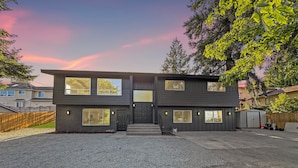 Een modern huis met twee verdiepingen, een veranda, grote ramen en een garage.