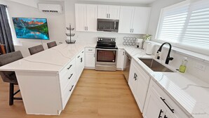 Een moderne keuken met witte kastjes, een centraal eiland, een inbouwoven en een magnetron.