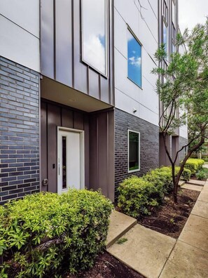 A modern building with a brick facade, a white door, and a small window. - Modern 3-bedroom townhome in Dallas with Private Rooftop, Private Garage, Grill (Dallas)