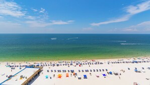 A beach with numerous umbrellas and sun loungers, a pier, and the ocean in the background. - Seawind 1502 (Gulf Shores)
