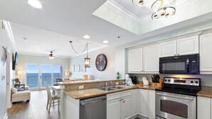 A modern kitchen with white cabinets, stainless steel appliances, a granite countertop, and a view to the outside. - Seawind 1502 (Gulf Shores)