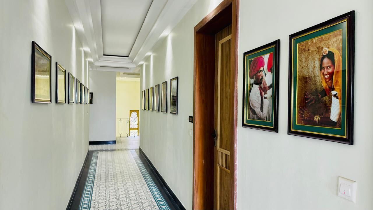 A hallway with framed pictures on the walls, a patterned floor, and a wooden door.