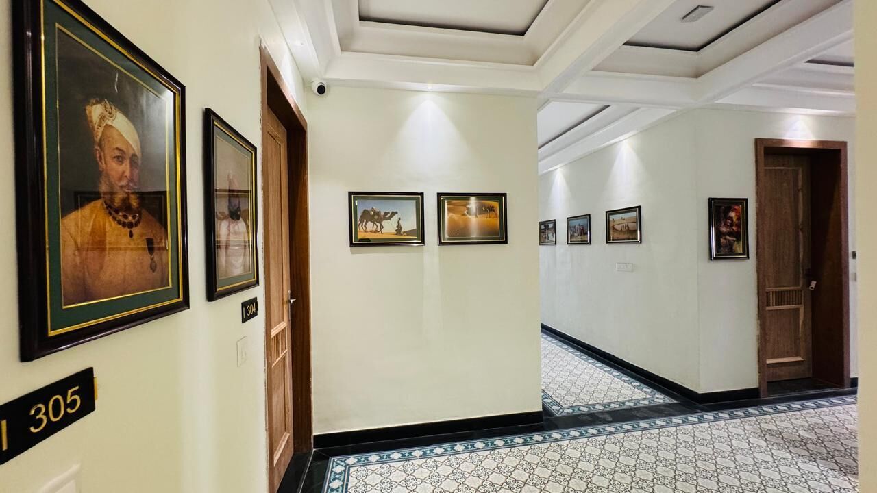 A hallway with framed pictures on the walls, a tiled floor, and a number sign indicating room 305.