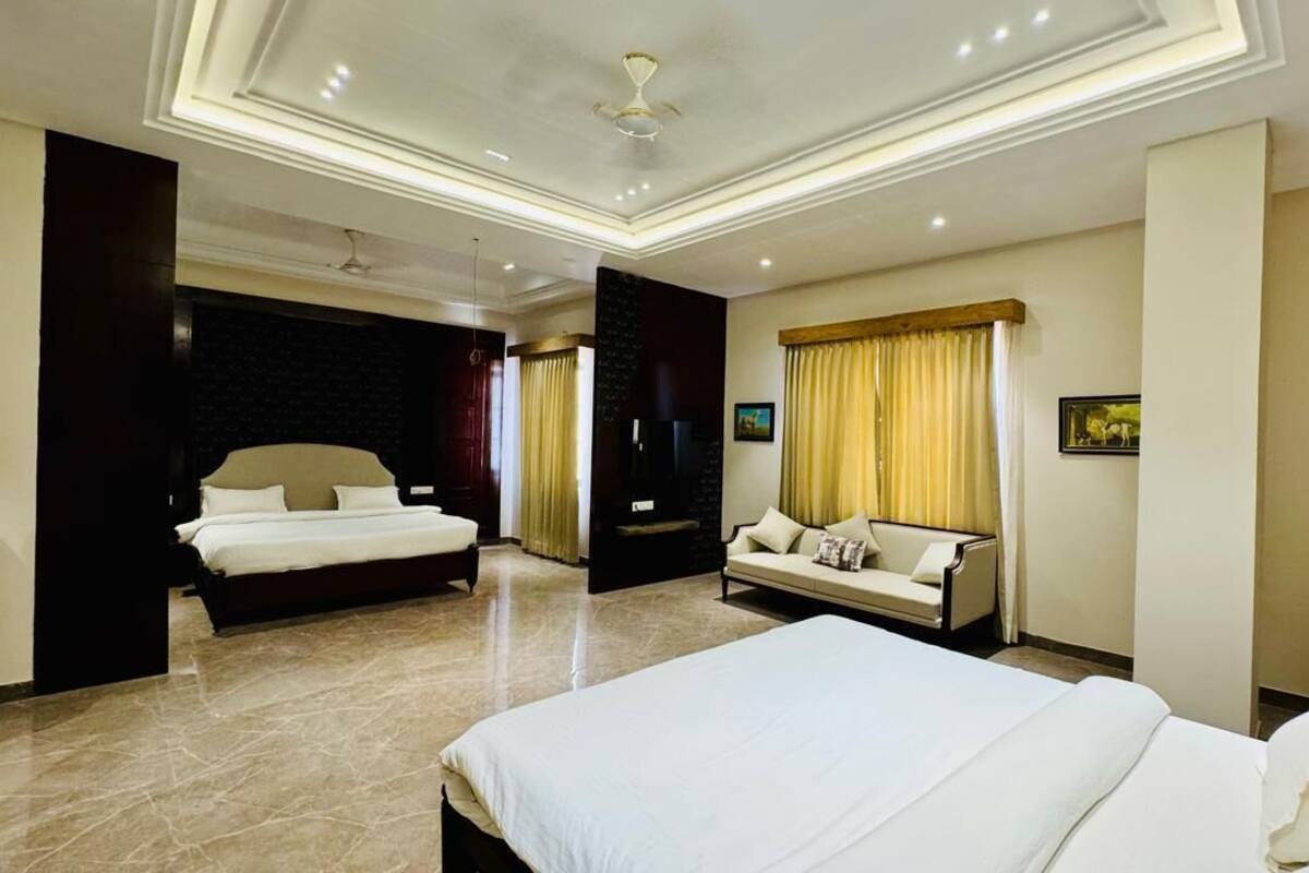 Habitación de hotel con una cama grande, un sofá, un televisor y un ventilador de techo.