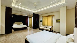 Habitación de hotel con una cama grande, un sofá, un televisor y un ventilador de techo.