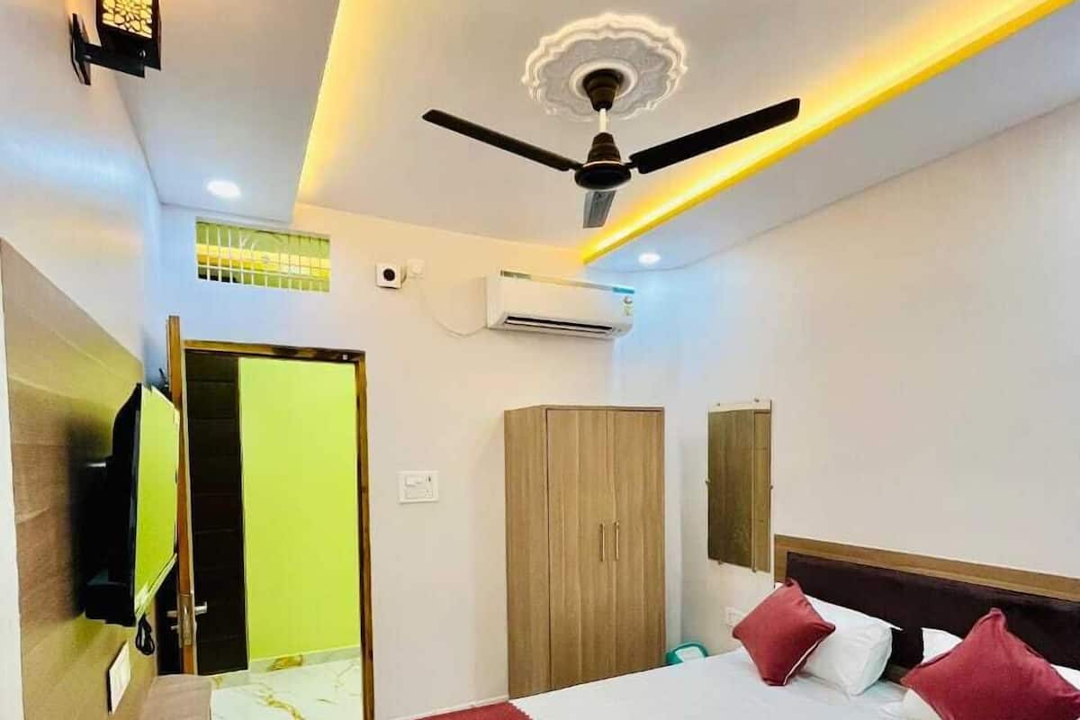 A hotel room with a bed, a ceiling fan, an air conditioning unit, a wardrobe, and a seating area.