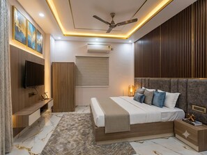 A modern bedroom with a bed, TV, wardrobe, and ceiling fan. - Hotel PVS Grand (Varanasi)