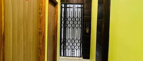 A hallway with wooden doors, a metal gate, and a marble floor.