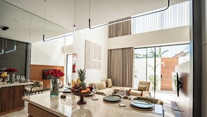A modern kitchen with a marble countertop, a dining area with a sofa, and a large window with curtains. - Charming 2-bedroom Oasis Smart Apartment with AC, WiFi in marvelous Bali (Bali)