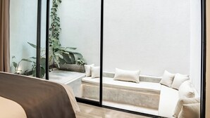 A modern bedroom with a large bed, a sofa, and a view through a sliding glass door to an outdoor area with plants. - Charming 2-bedroom Oasis Smart Apartment with AC, WiFi in marvelous Bali (Bali)