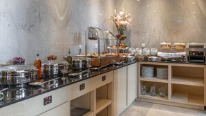 A modern hotel kitchen with marble walls, buffet counters with food and drink containers, and a decorative centerpiece. - Landmark Hotels & Suites (Jeddah)
