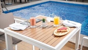 A poolside table with drinks, a small plant, and a slice of cheesecake. - Landmark Hotels & Suites (Jeddah)