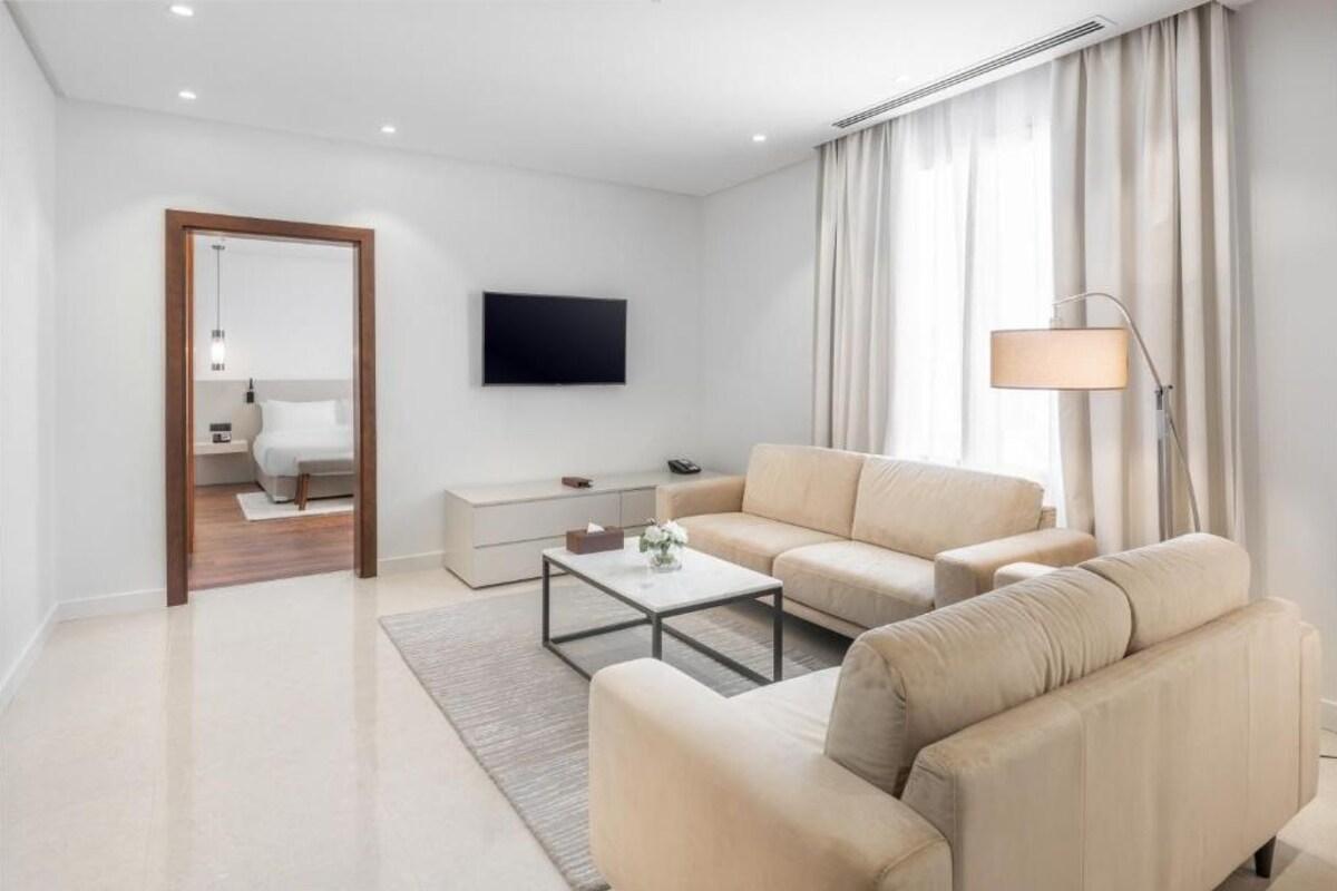 A modern living room with a sofa, coffee table, and a flat-screen TV mounted on the wall.