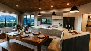 Une cuisine moderne dotée d’un îlot central, d’une table à manger en bois et de luminaires suspendus.