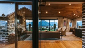 Un vaste espace de vie doté d’une grande fenêtre offrant une vue sur les montagnes, un coin salon confortable avec un canapé et des fauteuils, et un plancher en bois.
