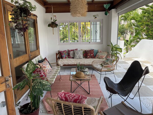 A cozy living area with a sofa, chairs, a coffee table, and hanging plants.