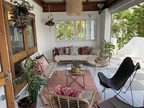 A cozy living area with a sofa, chairs, a coffee table, and hanging plants.